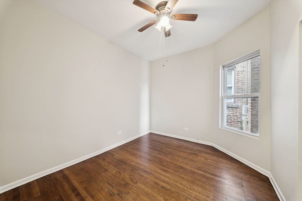 6520 South Ellis Avenue Chicago, IL 60637 - Photo 17 of 38 an empty room with wooden floor fan and windows