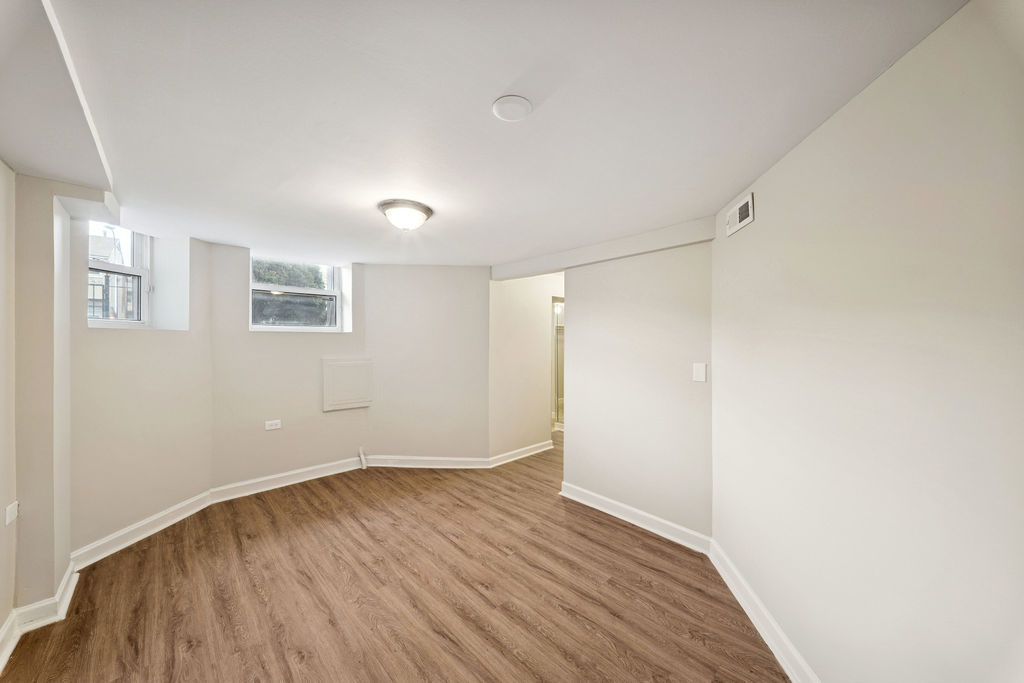 6520 South Ellis Avenue Chicago, IL 60637 - Photo 25 of 38 a view of an empty room with wooden floor and a window