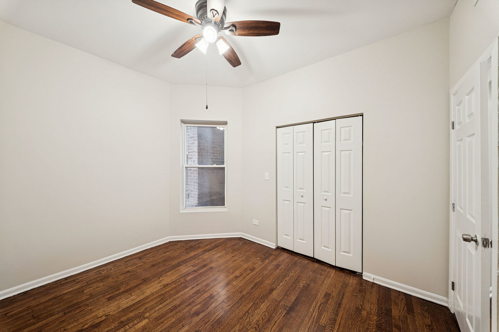 6520 South Ellis Avenue Chicago, IL 60637 - Photo 7 of 38 an empty room with wooden floor chandelier fan and windows