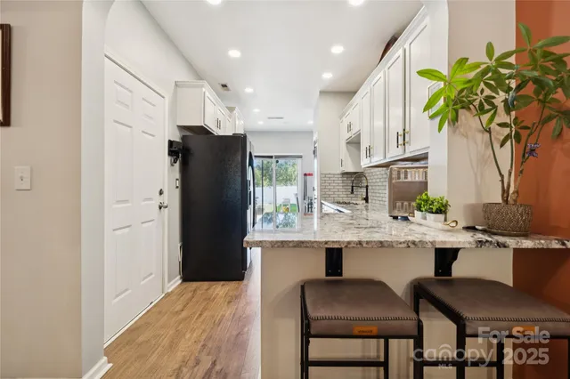 a kitchen with stainless steel appliances granite countertop a refrigerator and a dining table