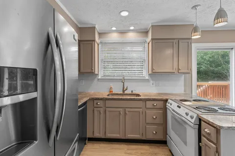 a kitchen with stainless steel appliances granite countertop a refrigerator a sink and white cabinets