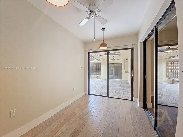 an empty room with wooden floor fan and windows