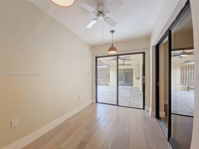 an empty room with wooden floor fan and windows