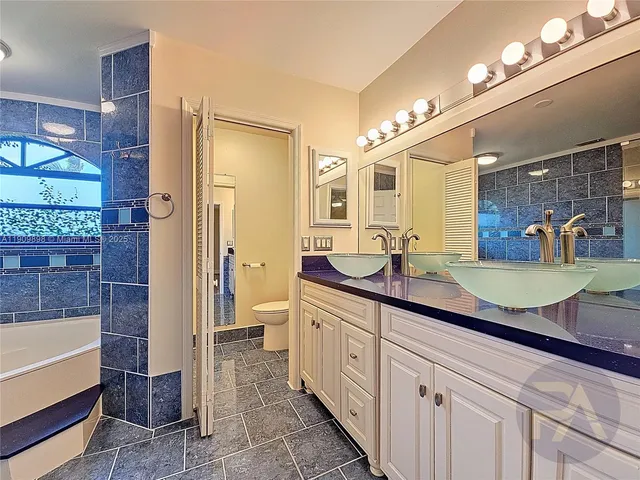 a spacious bathroom with a granite countertop sink a mirror and a shower