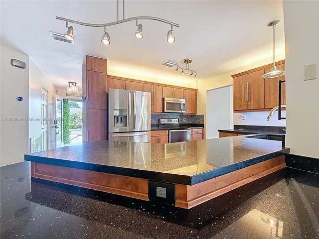 a view of kitchen with stainless steel appliances granite countertop a sink and refrigerator