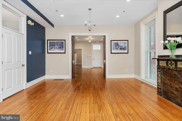 a view of a hallway with wooden floor and a chandelier