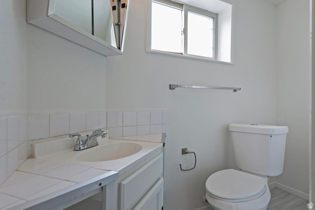 1722 Kimsbrough Road Sandy, UT 84092 - Photo 22 of 29 Bathroom featuring a corner vanity with an integrated sink, white tile backsplash, and coordinating medicine cabinet