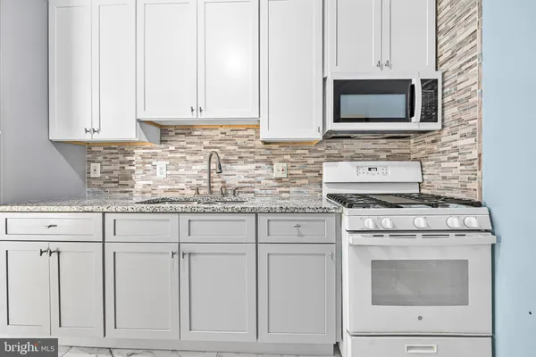 a kitchen with granite countertop white cabinets and stainless steel appliances