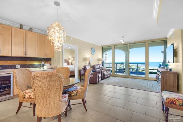 a view of a dining room and livingroom with furniture large windows and a chandelier