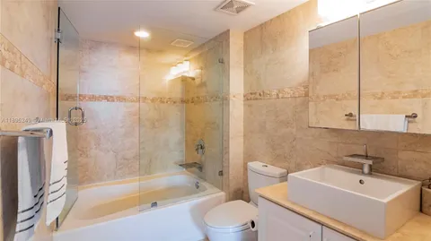 a bathroom with a bathtub shower sink vanity and toilet