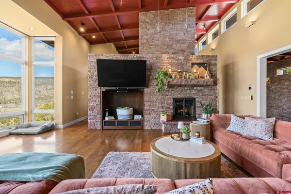 a living room with furniture a fireplace a flat screen tv and a large window