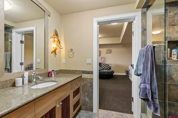 a en suite bathroom with a granite countertop sink and a mirror