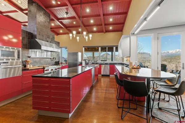 a dining hall with stainless steel appliances kitchen island granite countertop a table chairs and a living room view