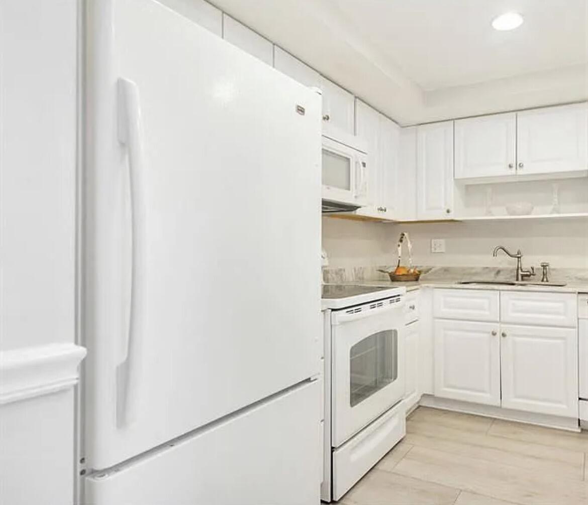 3800 Washington Road, Unit 310 West Palm Beach, FL 33405 - Photo 4 of 14 a kitchen with granite countertop white cabinets and white appliances