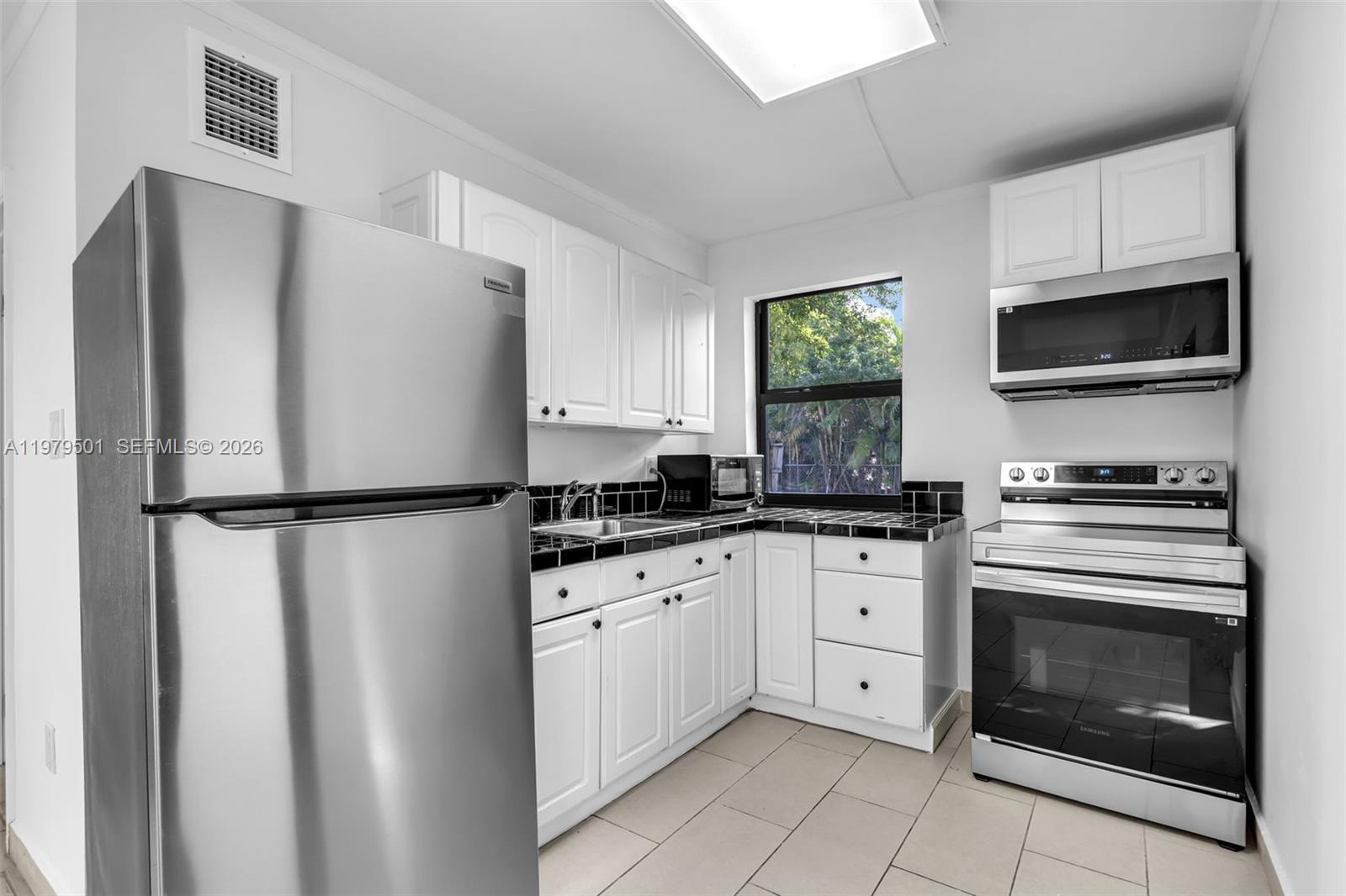 130 Southwest 31st Court, Unit 2 Miami, FL 33135 - Photo 7 of 14 a kitchen with white cabinets stainless steel appliances and a refrigerator