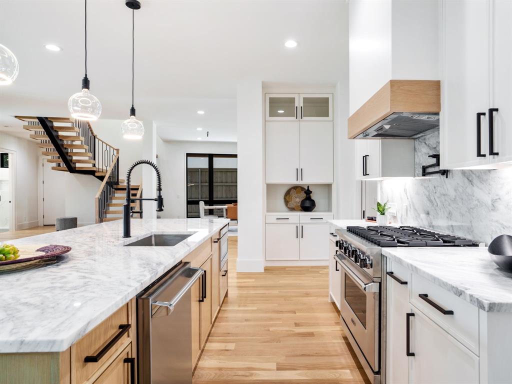 4010 Sperry Street Dallas, TX 75214 - Photo 8 of 40 Two tone kitchen featuring light stone counters, pendant lighting, stainless steel appliances, light wood finished floors, and glass insert cabinets