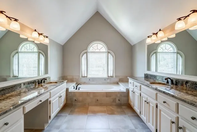 a large spacious bathroom with a granite countertop tub a double vanity sink and a large mirror