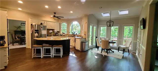 a dining room with stainless steel appliances granite countertop furniture wooden floor and a large window