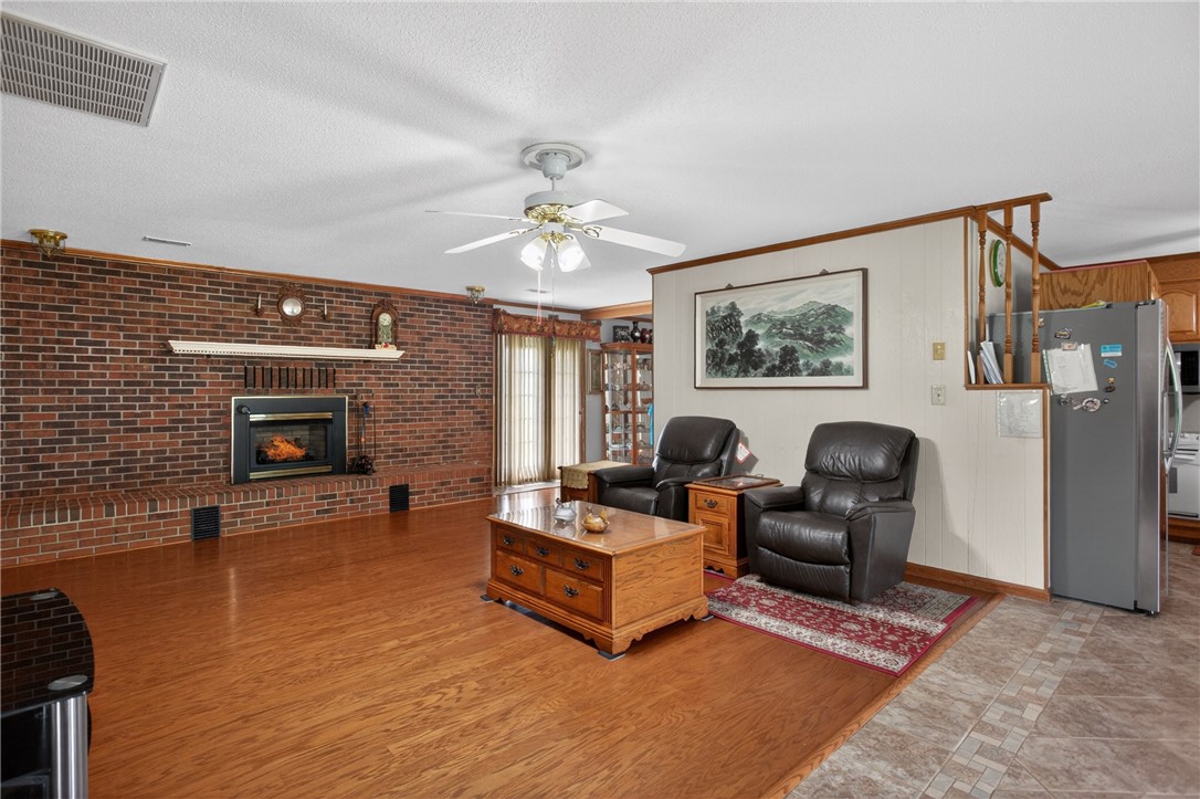 145 State Rd S-4-935 Pendleton, SC 29670 - Photo 41 of 47 A spacious living area showcasing a brick fireplace with a raised hearth, complemented by warm wood flooring.