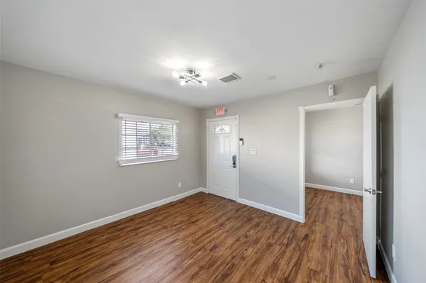 a view of an empty room with wooden floor and a window