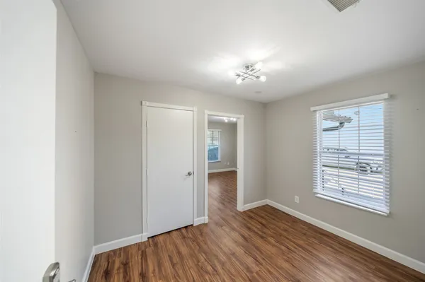 a view of an empty room with a window and wooden floor