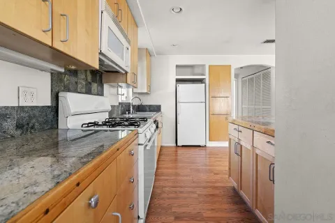 a large kitchen with a center island wooden floor and stainless steel appliances