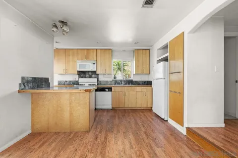 a view of a kitchen with a sink and dishwasher with wooden floor