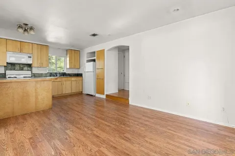 a kitchen with stainless steel appliances granite countertop a stove top oven a sink dishwasher and a refrigerator with wooden floor