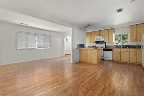 a kitchen with stainless steel appliances granite countertop a stove a sink and white cabinets with wooden floor