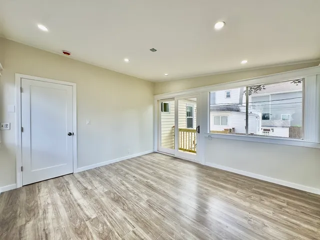 a view of an empty room with window and wooden floor