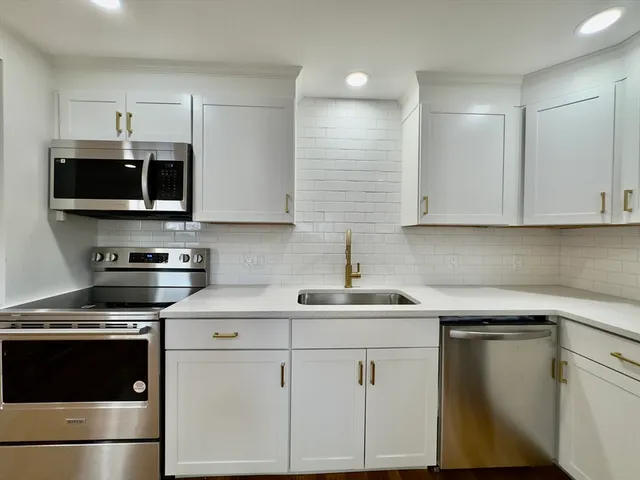 a kitchen with white cabinets stainless steel appliances and sink