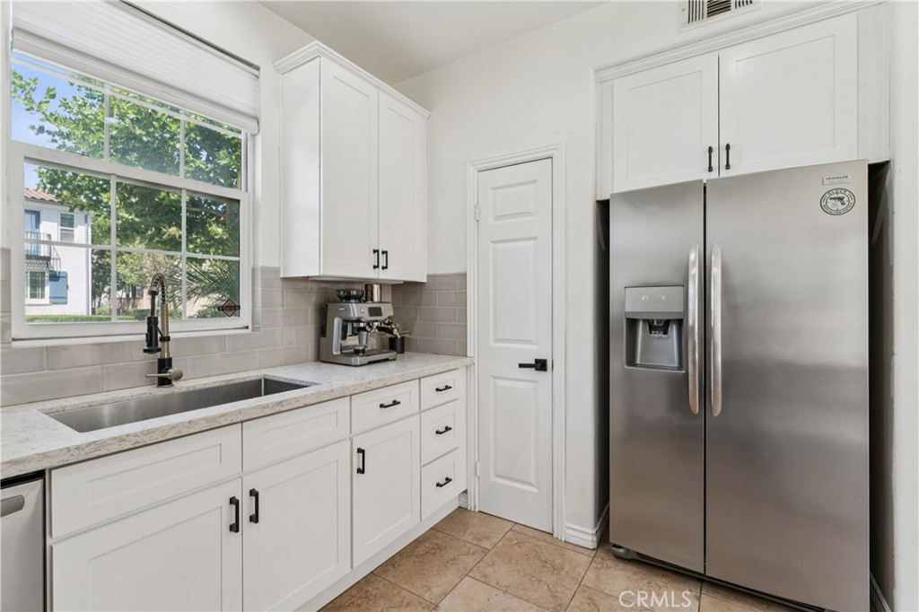 4155 Windspring Street Corona, CA 92883 - Photo 15 of 38 a kitchen with granite countertop a refrigerator a sink and white cabinets