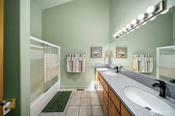 a spacious bathroom with a granite countertop double vanity sink a mirror and a shower