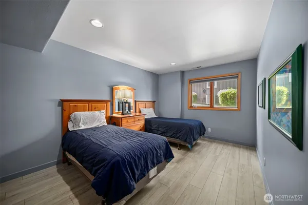 a bedroom with two beds and a dresser next to a window