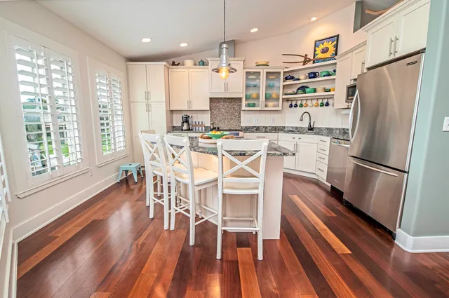 a kitchen with stainless steel appliances a refrigerator a stove top oven and a dining table with wooden floor