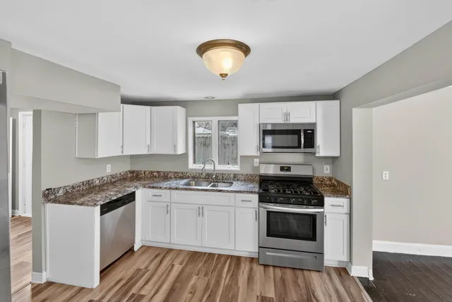 a kitchen with a stove white cabinets and white appliances