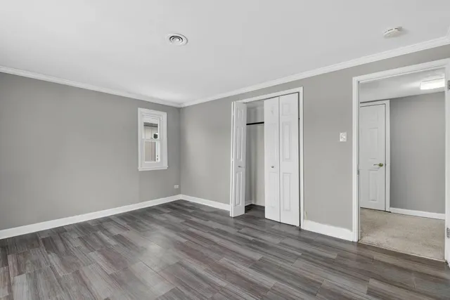 a view of an empty room with wooden floor and closet