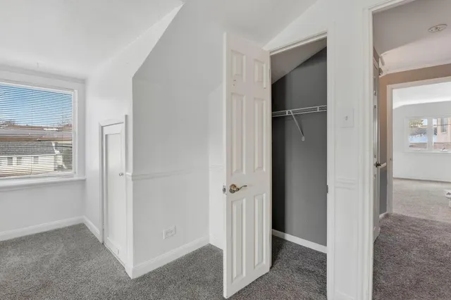 a view of an empty room with closet and a window