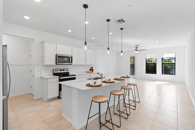 a kitchen with stainless steel appliances kitchen island granite countertop a sink a stove a dining table and chairs