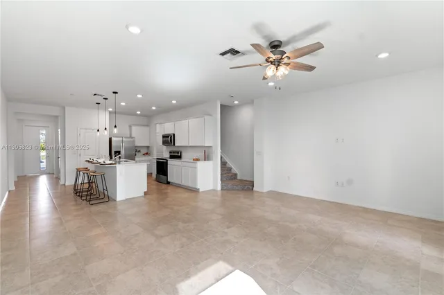 a view of kitchen with kitchen island stainless steel appliances refrigerator stove and white cabinets