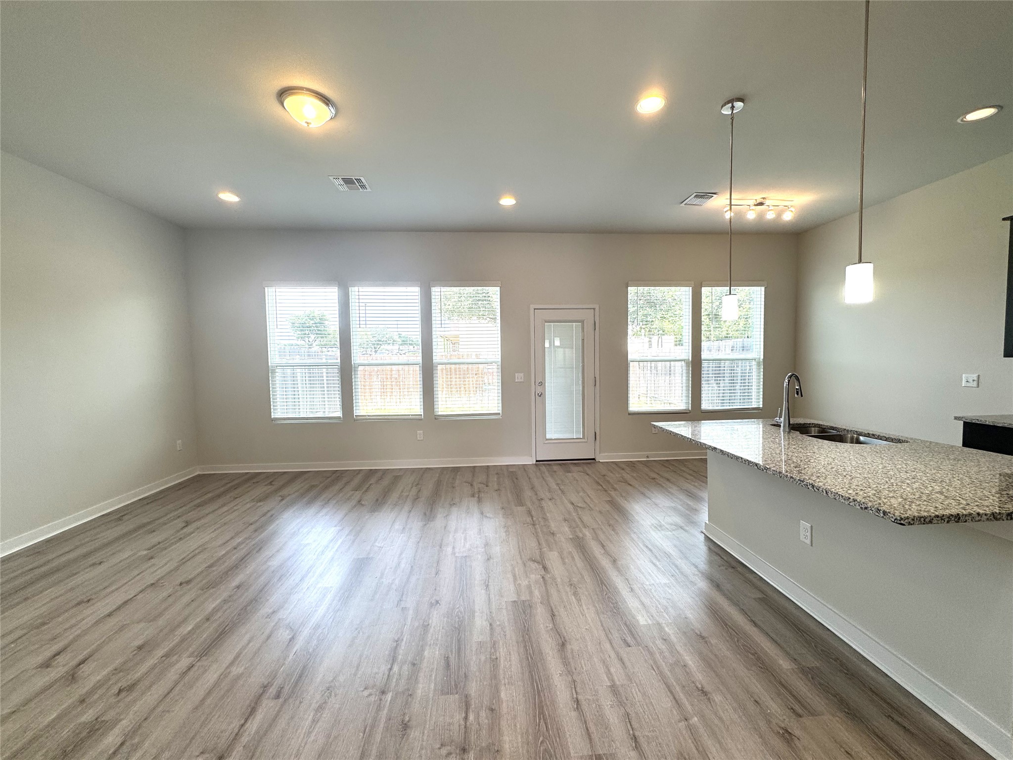 15102 Ryman Road Pflugerville, TX 78660 - Photo 2 of 12 wooden floor and windows in an empty room