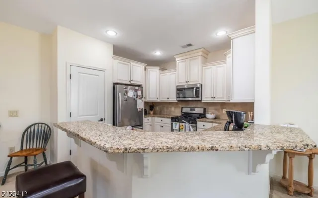 a kitchen with stainless steel appliances granite countertop a sink refrigerator and cabinets