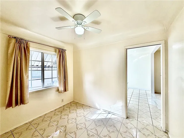 an empty room with wooden floor chandelier fan and windows