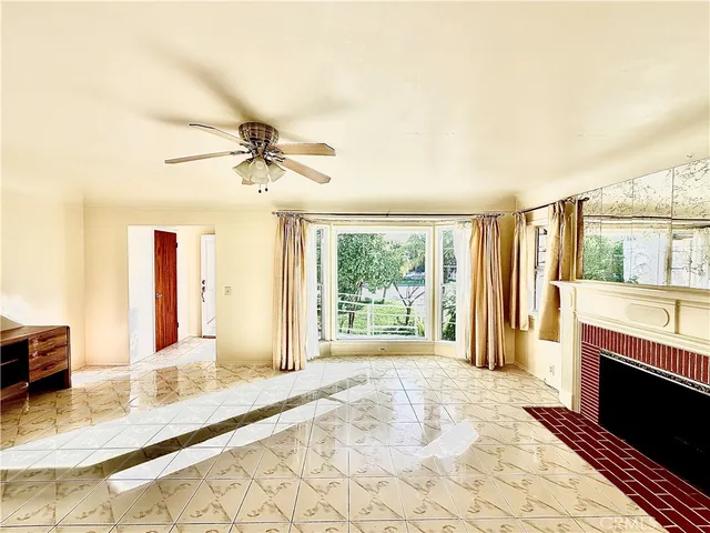 a view of a livingroom with a fireplace a ceiling fan and windows