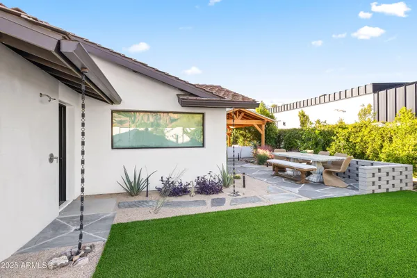 a view of a backyard with table and chairs potted plants and a bench