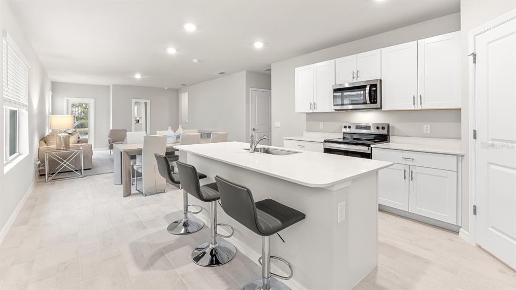 2994 Northeast 21st Ct Road Ocala, FL 34479 - Photo 6 of 9 a kitchen with stainless steel appliances a sink a stove a refrigerator cabinets and chairs