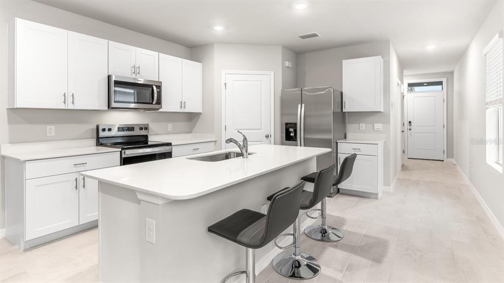 2994 Northeast 21st Ct Road Ocala, FL 34479 - Photo 7 of 9 a kitchen with stainless steel appliances a sink a stove a refrigerator cabinets and a dining table