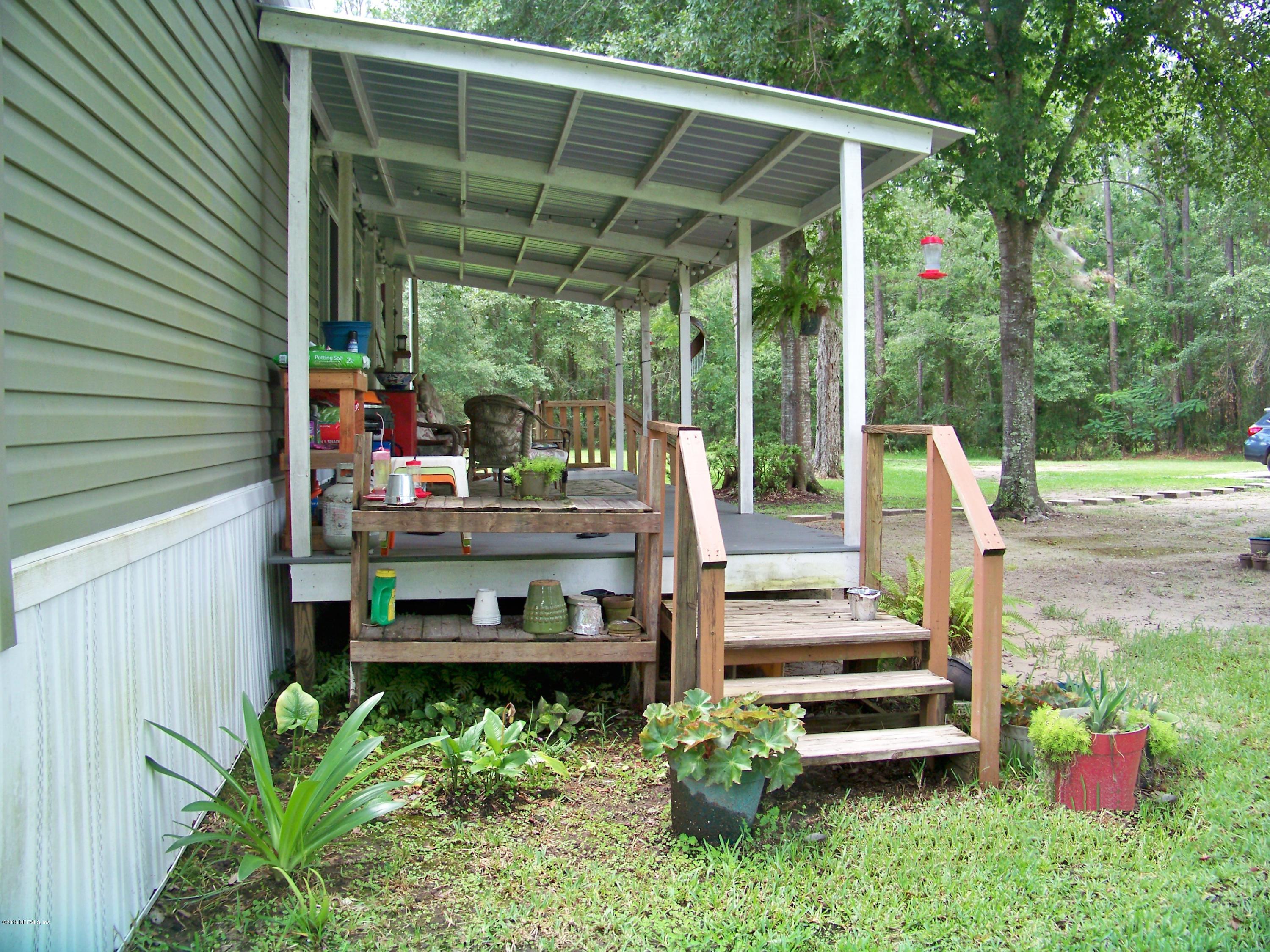 54314 Lawhon Road West Callahan, FL 32011 - Photo 26 of 30 a view of a patio with table and chairs potted plants with floor to ceiling window and wooden fence