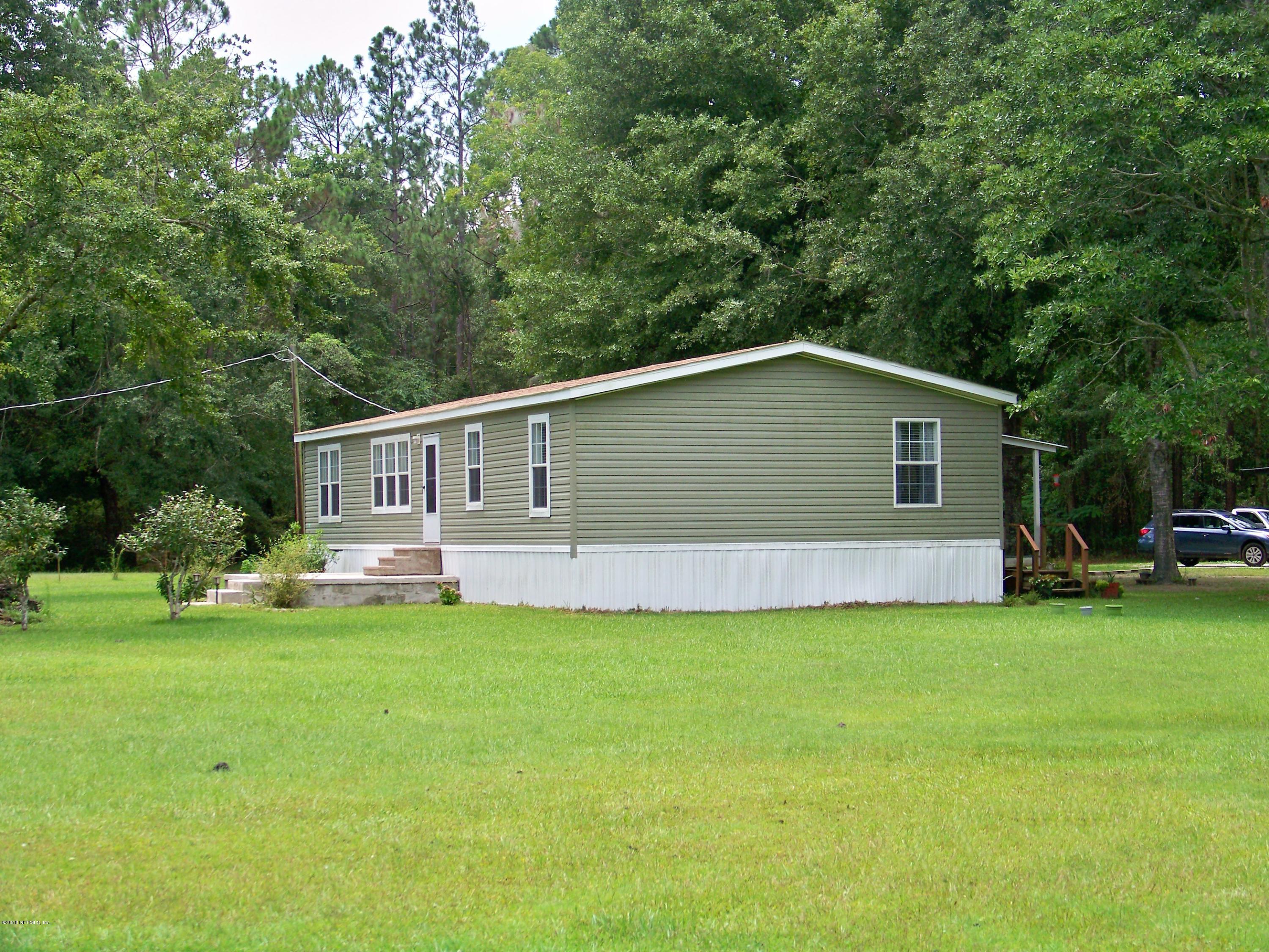 54314 Lawhon Road West Callahan, FL 32011 - Photo 28 of 30 a house that is sitting in the grass with large trees and plants