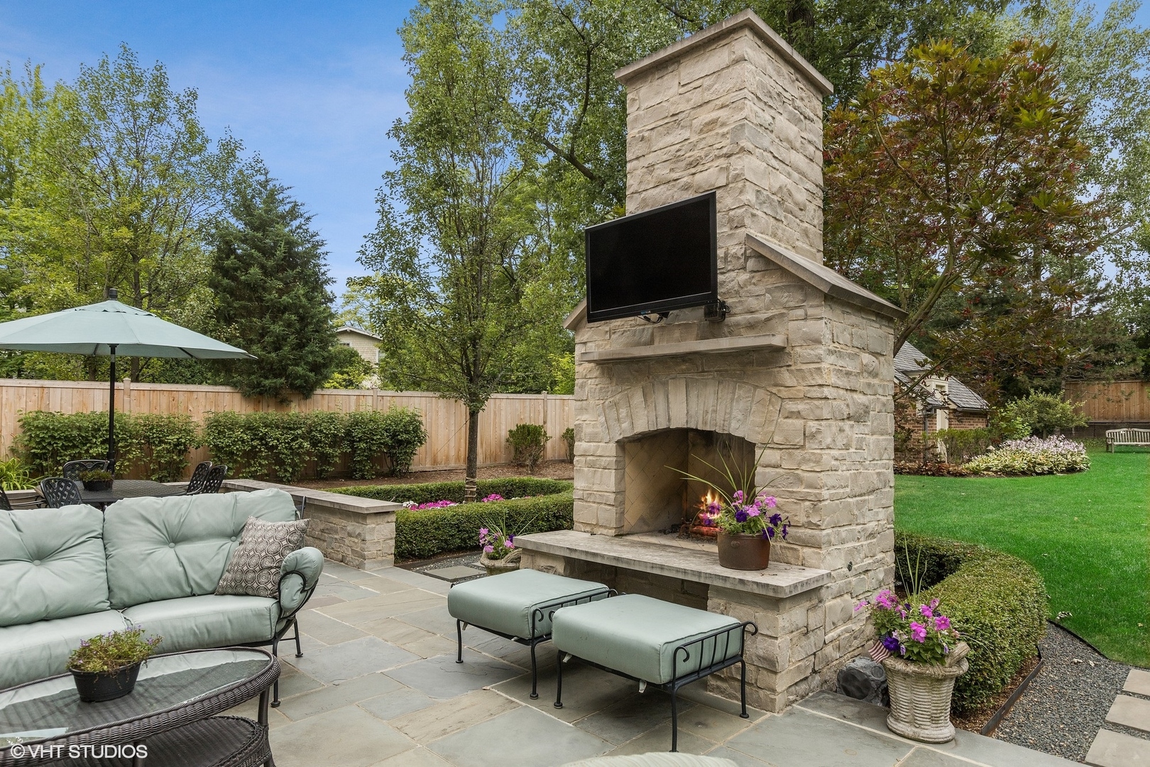 725 Walden Road Winnetka, IL 60093 - Photo 15 of 84 a view of a patio with couches table and chairs under an umbrella with a fire pit